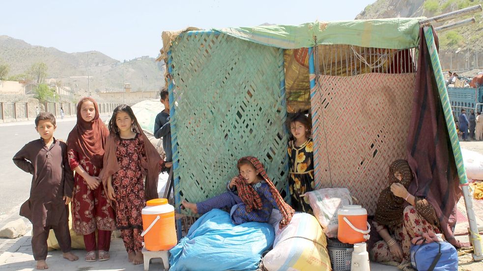 Afghanische Flüchtlinge sitzen mit ihren Habseligkeiten am Grenzübergang Torkham. (Archivbild) Foto: Nabila Lalee/dpa