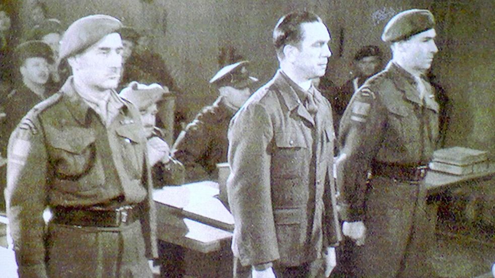 Dieses Foto von Kurt Meyer (Mitte) entstand, als er sich am 10. Dezember 1945 in der Auricher Kaserne vor einem kanadischen Kriegsgericht verantworten musste. Foto: Barney J. Gloster / Library and Archives Canada