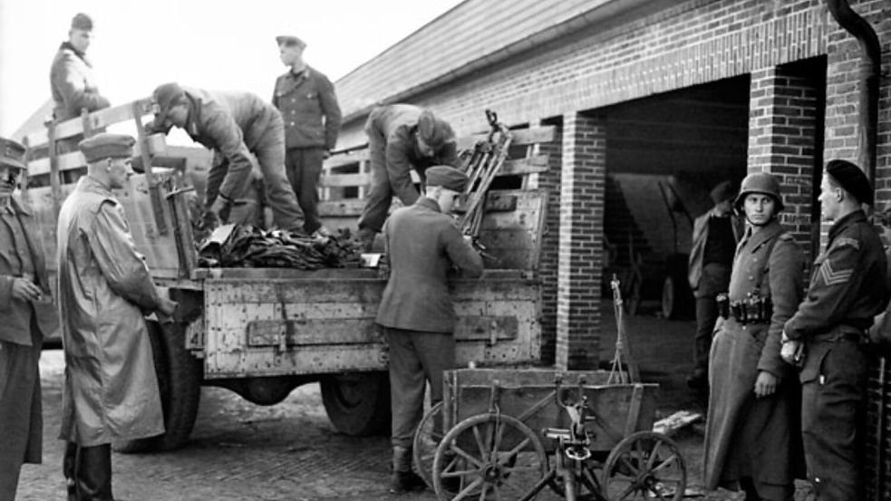Ein kanadischer Soldat (ganz rechts) beobachtet am 7. Mai 1945 das Einlagern deutscher Waffen auf dem Gelände der Auricher Blücher-Kaserne. Foto: © Library and Archives Canada