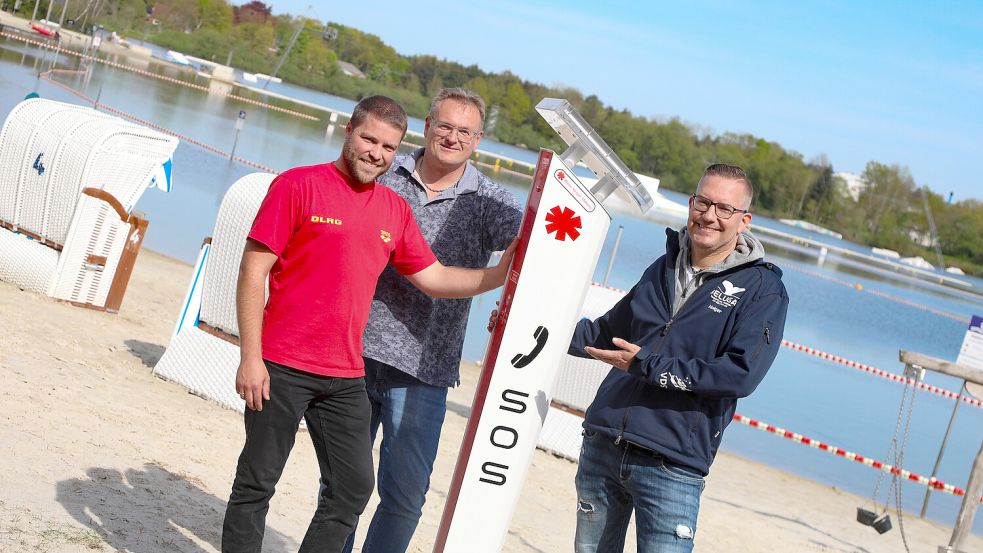 Michael Rieken (2. Vorsitzender DLRG Aurich, von links), Jens Reinecke (Stadt Aurich) und Holger Janssen (Vorsitzender TC-Beluga) freuen sich über die neuen Notrufsäulen am Badesee. Foto: Romuald Banik