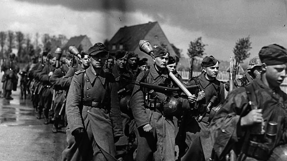 Bewaffnete deutsche Soldaten haben ihre Stellungen im Umland im Zuge der bedingungslosen Kapitulation verlassen und betreten am 5. Mai 1945 das Gelände der Auricher Blücherkaserne. Foto: © Library and Archives Canada