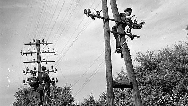 Angehörige der 7th Infantry Brigade (Rifles), Canadian Army Occupation Force (C.A.O.F.), reparieren am 12. August 1945 eine Telefonleitung in Aurich. Foto: © Library and Archives Canada