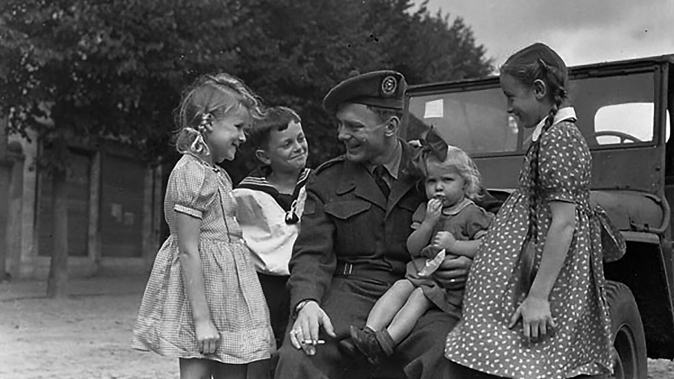 Private Murray Dorey von der Canadian Army Occupation Force (C.A.O.F.) gibt deutschen Kindern in Aurich Schokolade. Die Aufnahme entstand Ende August 1945. Foto: © Library and Archives Canada