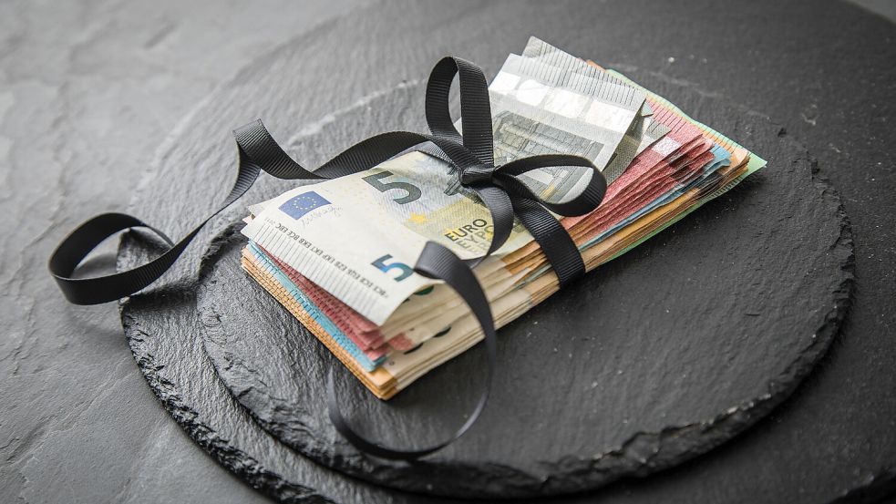 Ein Bündel Geldscheine ist mit einer Schleife umwickelt Foto: Christin Klose/dpa/dpa-tmn