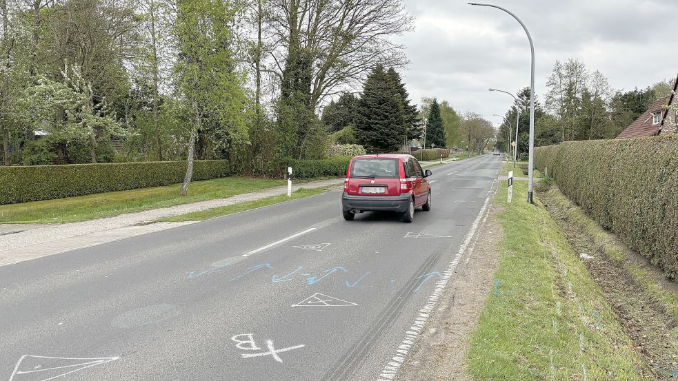 Ein Auto passiert in Halbemond die Laterne, gegen die die 17-Jährige mit ihrem Motorrad prallte. Die Polizei hat die Unfallstelle auf der Straße markiert. Foto: Thomas Dirks