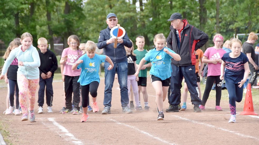 Auf die Plätze, fertig, los! Hier starten Schüler zu einem Sprint über 50 Meter. Mitschüler schauen ihnen dabei zu. Wilm Hicken (mit Starterklappe) gibt das Kommando.