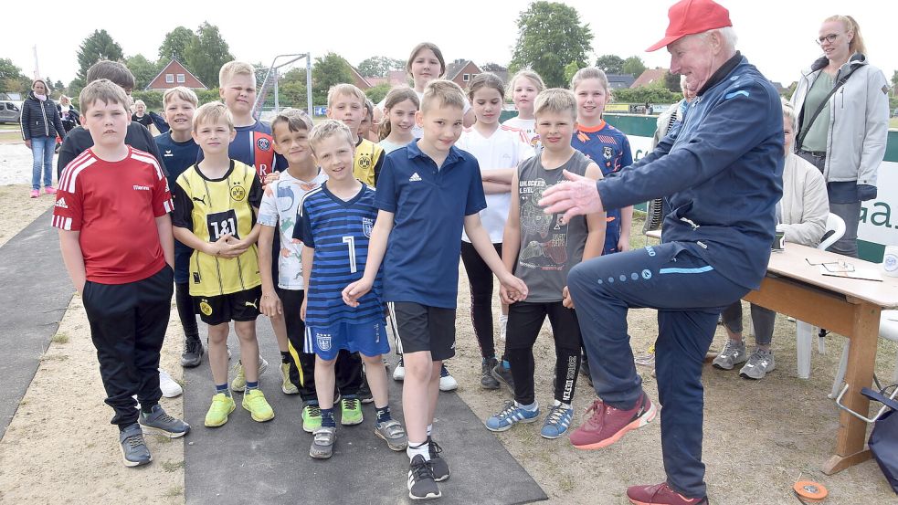 Eilert Janssen, Mitbegründer des Sportabzeichentags, zeigt Schülern, was sie beim Weitsprung beachten sollten. Foto: Thomas Dirks