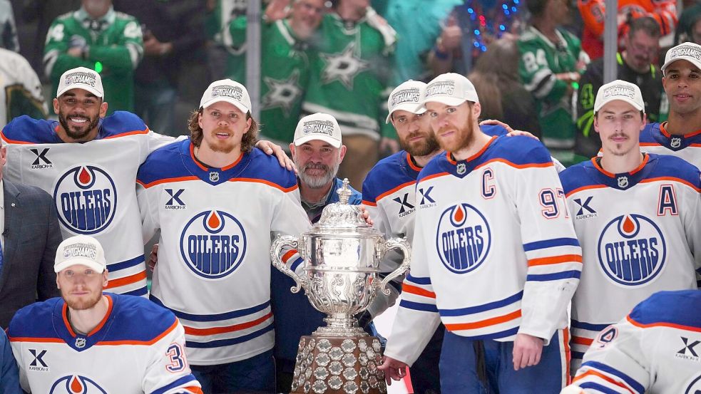 Leon Draisaitl posiert hinter Kapitän Connor McDavid mit dem Pokal für den Sieger der Western Conference. Foto: Julio Cortez/AP/dpa
