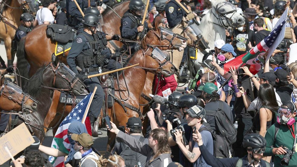 Demonstranten stoßen in Los Angeles mit berittenen Polizisten zusammen. Foto: Ethan Swope/AP/dpa