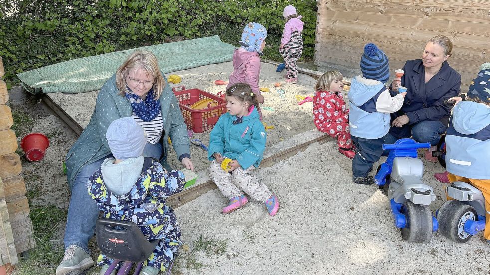 Sylvia Hinrichs (links) und Ildiko Plenter nutzen den Sonnenschein für eine Runde Sandkastenspiel mit den Kleinen Fröschen. Foto: Karin Böhmer