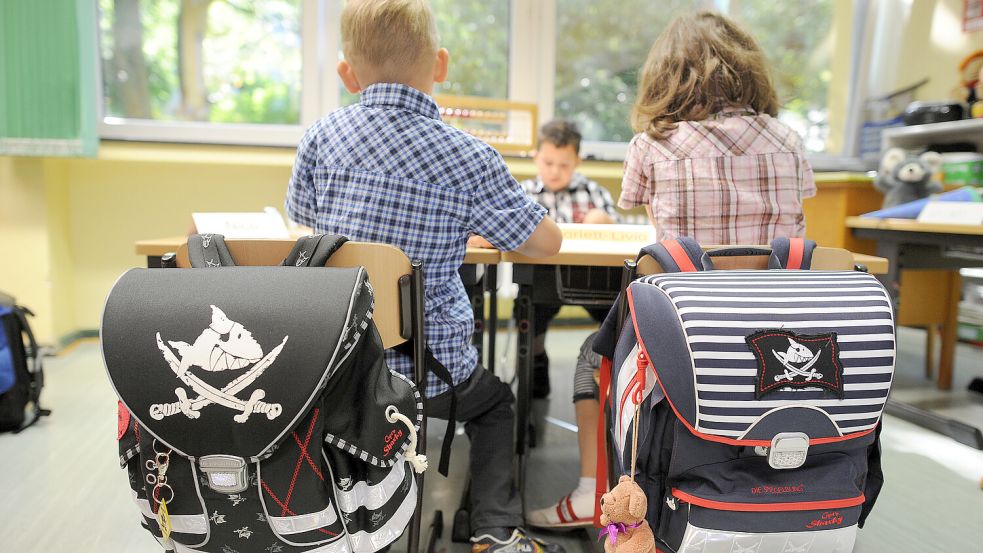 Zwei Kinder sitzen an ihrem ersten Schultag auf ihren Stühlen und malen Schultüten aus. Foto: DPA