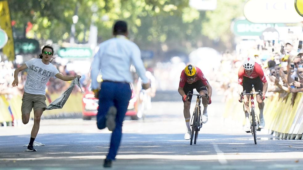 Während Jonas Abrahamsen und Mauro Schmid (r) in Toulouse um den Sieg sprinten, läuft ein Flitzer (l) auf die Zielgerade. Foto: Thibault Camus/AP/dpa