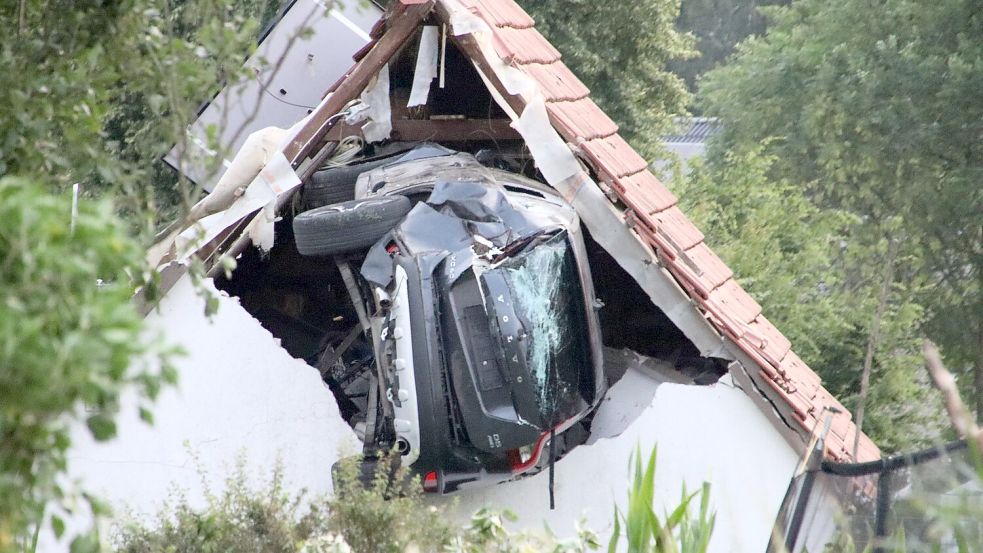 Das Auto liegt nach einem kurzen Flug seitlich in der Mauer einer Scheune. Foto: -/Moonshine Media/dpa