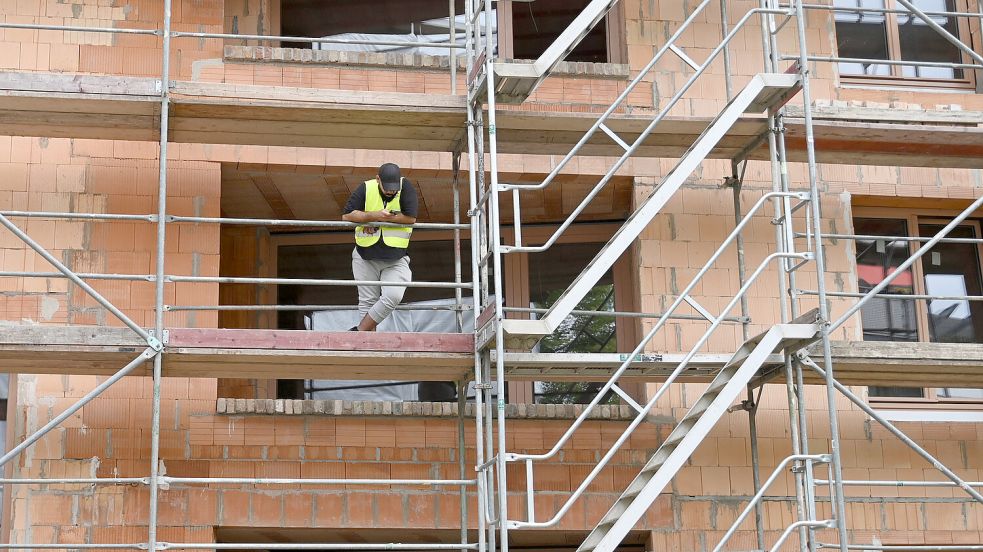 Ein Bauarbeiter steht auf einem Gerüst auf einer Baustelle. Foto: DPA