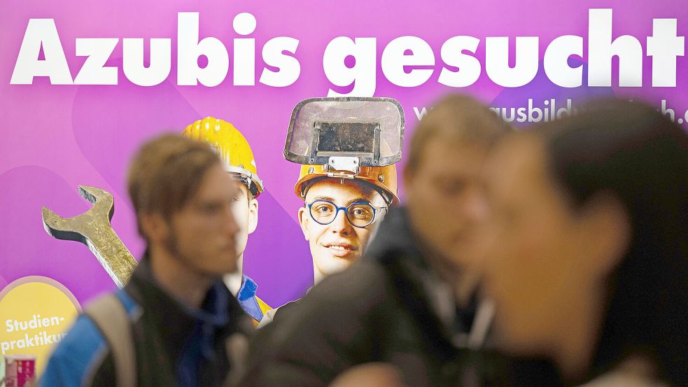 Besucher stehen auf einer Jobmesse vor dem Schriftzug „Azubis gesucht“. Foto: DPA