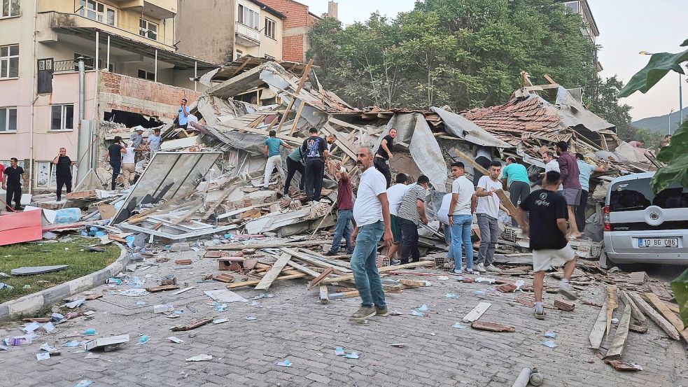Menschen beseitigen in Sindirgi die Trümmer eines eingestürzten Gebäudes. Foto: Bahadir Demirceviren/IHA/AP/dpa