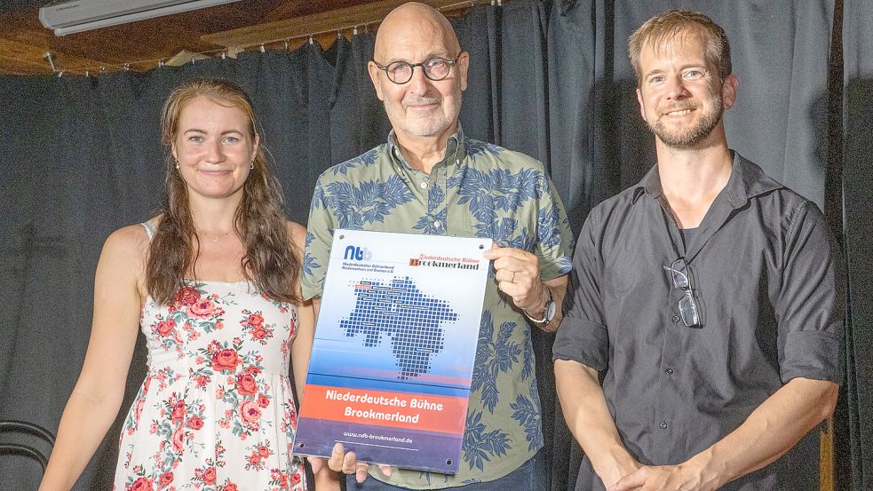 Der Präsident des Niederdeutschen Bühnenbund Niedersachsen Bremen, Arnold Preuß (Mitte), übergab das neue Namensschild an die Vorsitzenden der Niederdeutschen Bühne Brookmerland, Anika Camp und Jann Aden. Foto: Folkert Bents