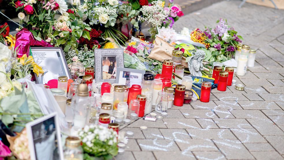 Zahlreiche Blumen und Kerzen stehen in der Innenstadt an einer Hauswand in der Achternstraße, wo am frühen Sonntagmorgen ein Mann durch Schüsse aus einer Polizeiwaffe tödlich verletzt wurde. Foto: Hauke-Christian Dittrich/dpa