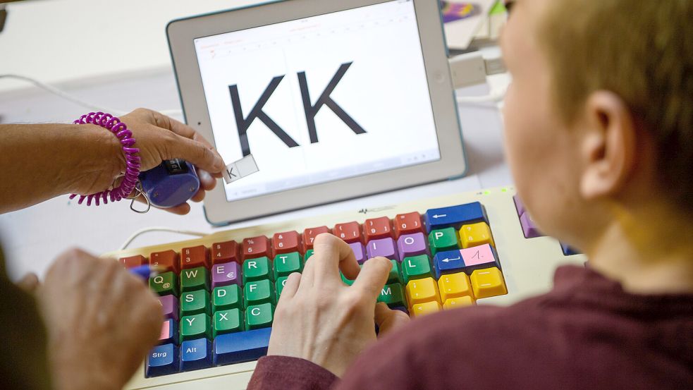Eine Therapeutin übt mit einem autistischen Kind das Erkennen und Schreiben von Buchstaben auf einer Tastatur. Foto: DPA
