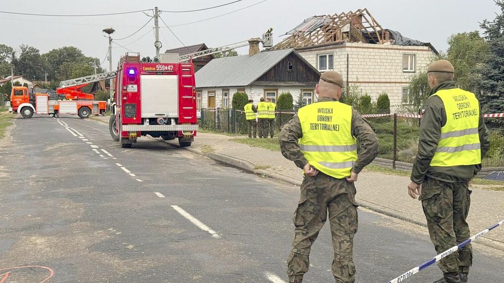 Feuerwehrleute und Beamte der Territorialen Verteidigung stehen in Wyryki bei Lublin, neben dem zerstörten Dach eines Hauses, nachdem russische Drohnen den polnischen Luftraum verletzt haben. Foto: dpa/Rafal Niedzielski