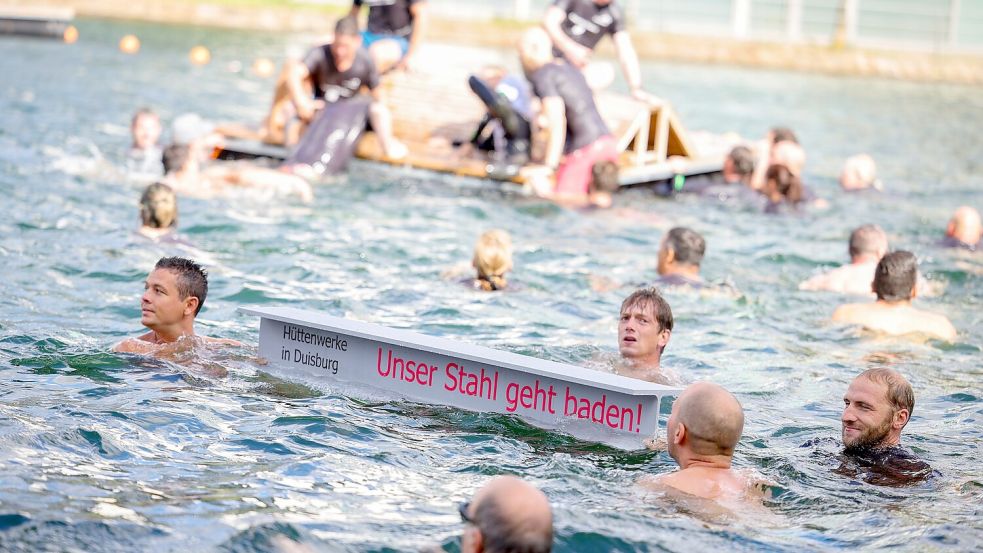 Ein symbolischer Stahlträger mit dem Slogan der Demo schwimmt im Duisburger Innenhafen zwischen zahlreichen Stahlbeschäftigten. Foto: Christoph Reichwein