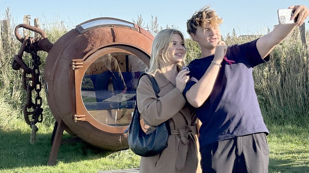 Die Handykamera auf sich und seine Freundin Gizem Güngör gerichtet, steht Jonas Moll vor der Ankerboje am Harlesieler Strand, ihrem außergewöhnlichen Domizil für diese Nacht. Foto: Susanne Ullrich