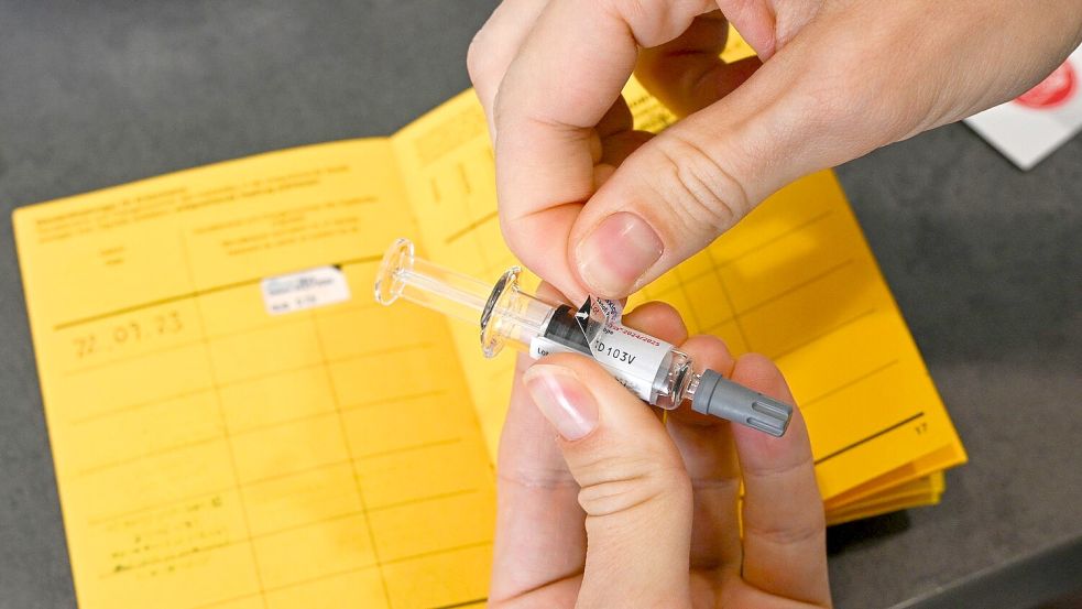 Ein Etikettenaufkleber mit der Chargen-Bezeichnung einer Grippeschutzimpfung wird von der Spritze abgezogen und in einen Impfpass eingeklebt. (Archivbild) Foto: Jens Kalaene