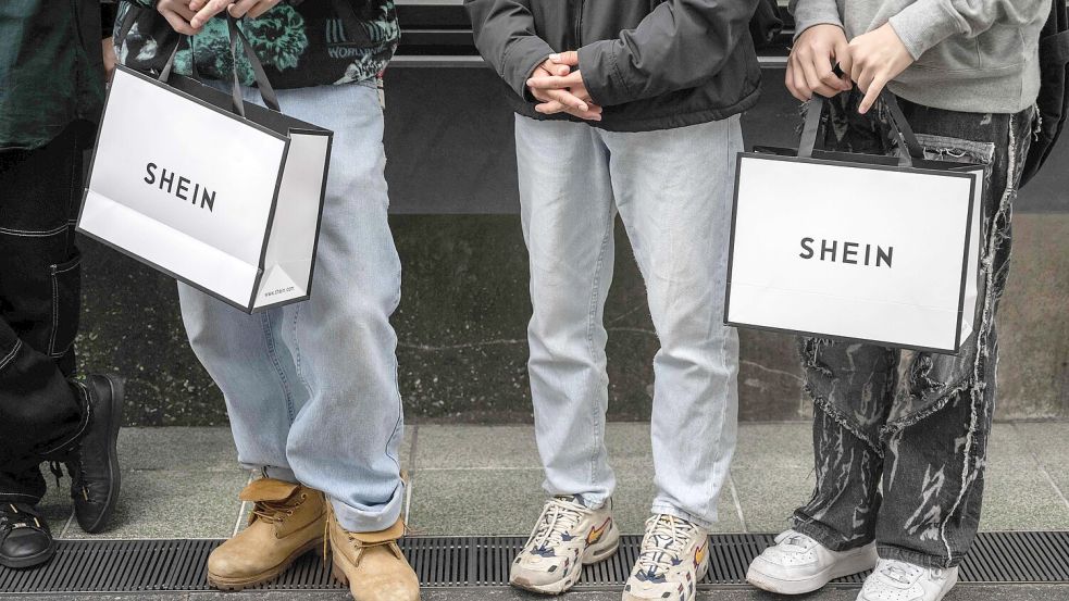 Menschen mit Shein-Einkaufstaschen vor dem ersten permanenten Ausstellungsraum des Online-Fast-Fashion-Giganten Shein in Tokio. Die ersten permanenten Geschäfte in Europa sollen in Frankreich eröffnet werden. Foto: AFP/YUICHI YAMAZAKI