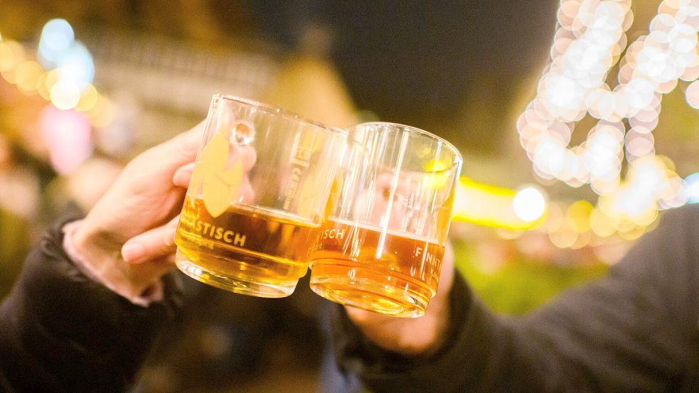 Zwei Besucher stoßen auf den Weihnachtsmarkt an. Foto: Julian Stratenschulte/DPA