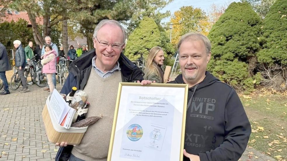 Bürgermeister Matthias Bludau (rechts) überreicht Ex-Ministerpräsident Stephan Weil (SPD) Urkunde und Verzehrpaket. Der einstige Landesvater wirbt nun als Botschafter für die „Hildesheimer Wald Wandernadel“. Foto: Matthias Bludau