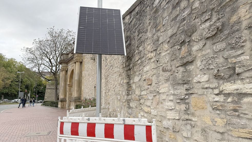 Am Heger Tor in Osnabrück halten Verkehrsteilnehmer inne: An der Mauer des Denkmals steht plötzlich eine Installation, eingezäunt durch Absperrschranken. Foto: Lukas Weinandy