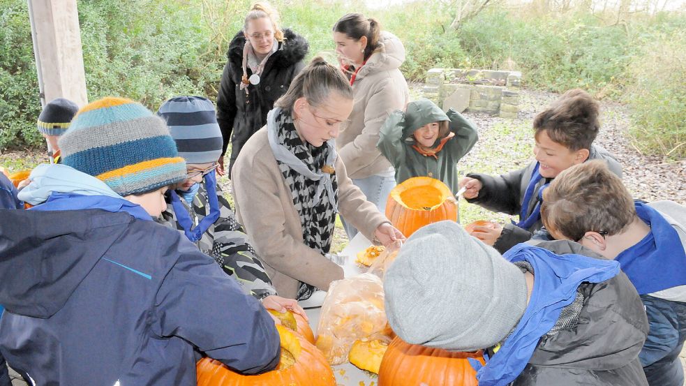 Die „Nordlichter“ trotzen dem stürmischen Inselwetter: Die Borkumer Pfadfinder haben kürzlich mit großem Eifer Kürbis-Gesichter für Halloween geschnitzt. Sara Hoffmann (hinten links) und Jil Strenger (vorne) begleiten die Kinder dabei. Foto: Udo Hippen