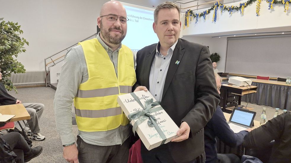 Florian Brechters (links) und Bürgermeister Florian Eiben mit der Unterschriftensammlung zum Erhalt der Grundschule Leybuchtpolder. Foto: Rebecca Kresse