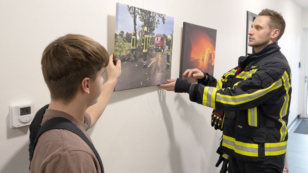Brookmerlands Feuerwehrpressewart Carsten Redenius hängt in den Fluren des neuen Gerätehauses Fotos von Einsätzen auf. Foto: Folkert Bents