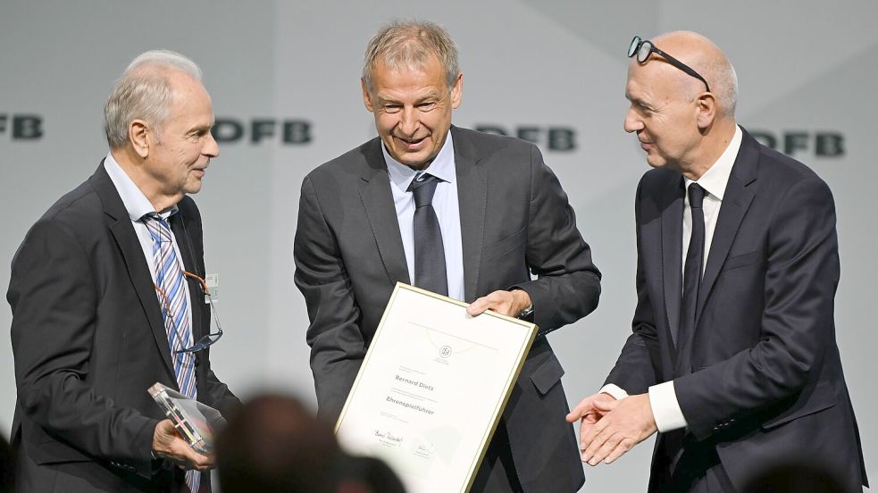 Bernard Dietz (l) wird von Jürgen Klinsmann und DFB-Präsident Bernd Neuendorf für die Ernennung zum Ehrenspielführer gratuliert. Foto: Arne Dedert