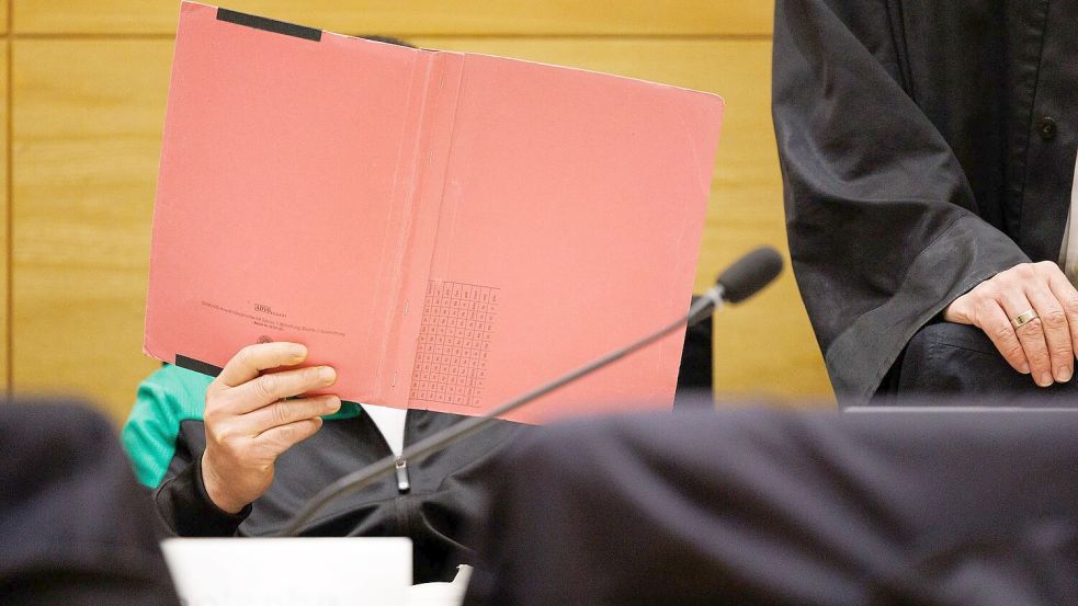 Einer der Angeklagten am Landgericht Bielefeld sitzt neben seinem Verteidiger und verdeckt sein Gesicht. Foto: Friso Gentsch