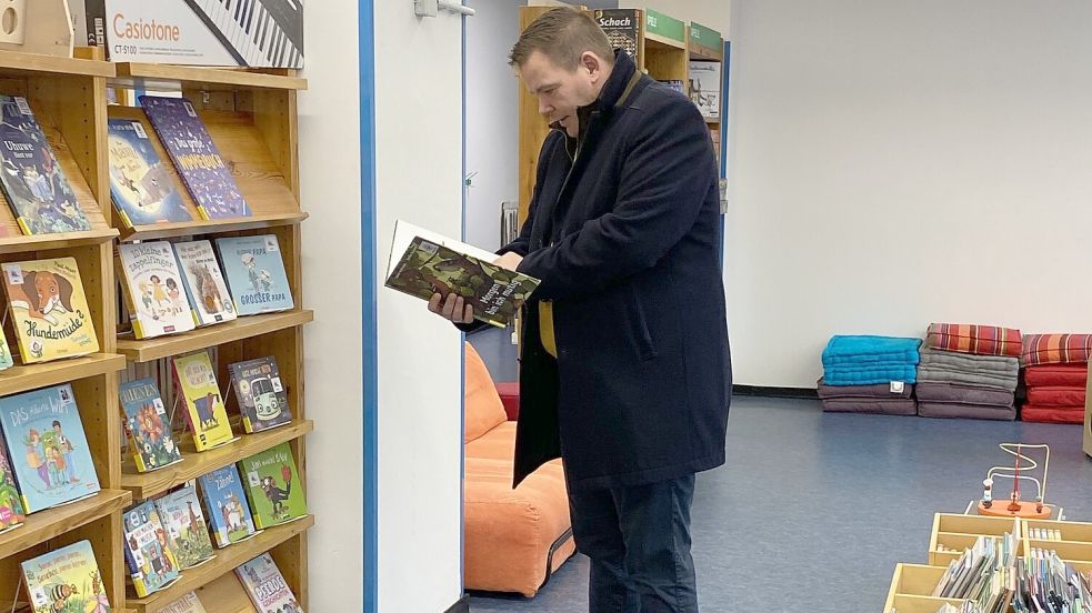 Bürgermeister Florian Eiben hat sich die neue Bibliothek schon angesehen. Warum er sich ausgerechnet das Buch: „Morgen bin ich mutig“ ausgewählt hat, bleibt sein Geheimnis. Foto: Stadt Norden