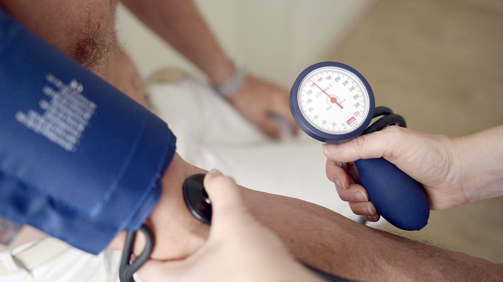 Eine Medizinerin misst den Blutdruck eines Patienten. In der Krummhörn fehlen Hausärzte. Symbolfoto: Maurizio Gambarini/dpa