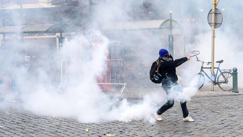 Ein Demonstrant schlägt bei den Protesten in Brüssel gegen einen Tränengasbehälter. Foto: Marius Burgelman/AP/dpa