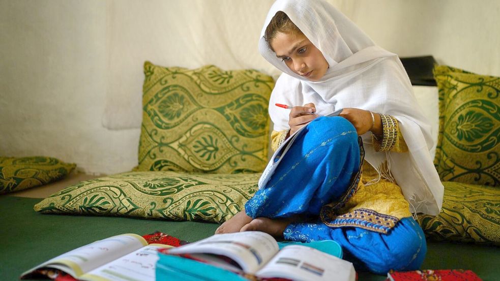 Die zehnjährige Hajira aus der afghanischen Provinz Nangarhar sitzt in einem Haus in einem abgelegenen Dorf östlich von Kabul über Schulbüchern und lernt. Foto: Elise Blanchard/Unicef/dpa