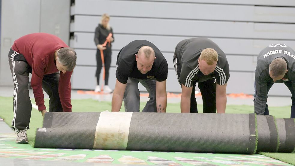 Mit vereinten Kräften verteilen die Helfer der SpVg Aurich den Rollrasen in der Sparkassen-Arena.Fotos: Wilfried Gronewold