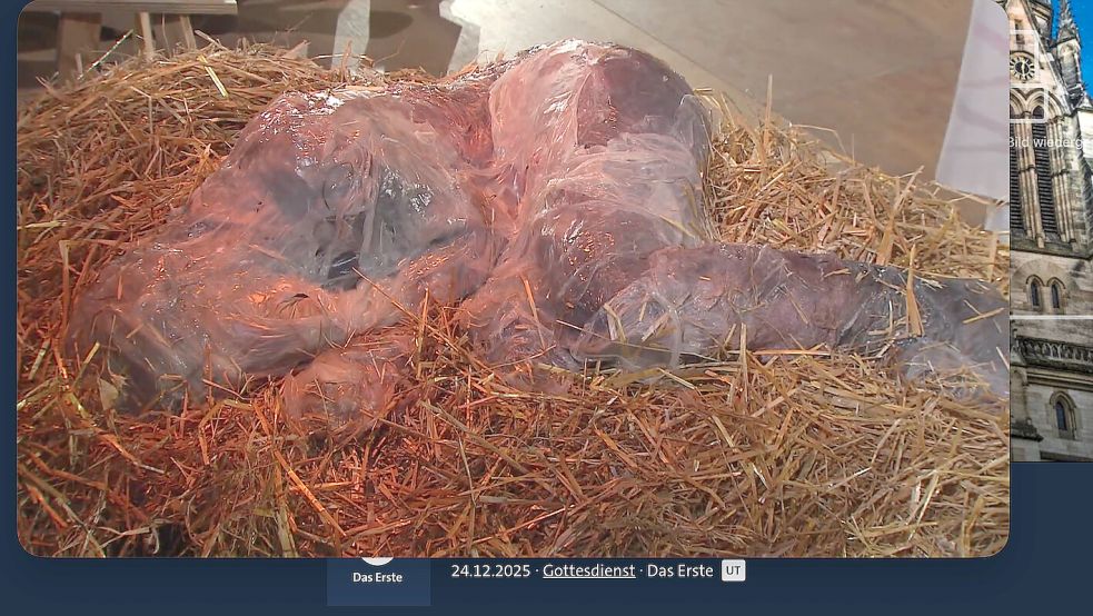 Diesen Anblick dürften manche Zuschauer der ARD-Christmette als eklig empfunden haben: In der Krippe liegt kein hölzernes Jesuskind, sondern ein unmenschlich aussehender Erwachsener. Foto: ARD Mediathek / mao