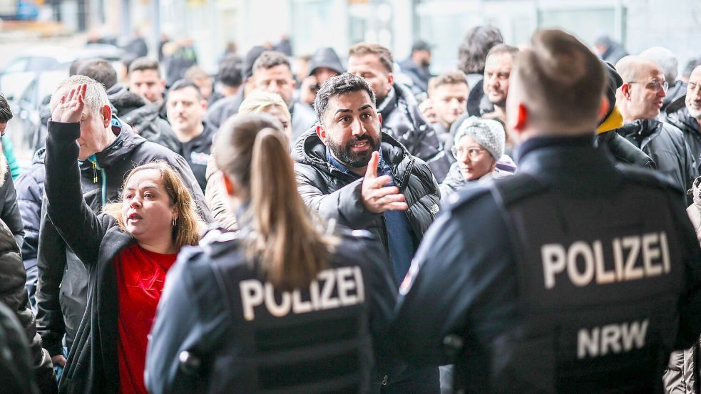 Aufgebrachte Kunden diskutieren vor der Sparkassenfiliale in Buer mit Polizeibeamten nach der Räumung des Vorraums der Filiale. Foto: Christoph Reichwein