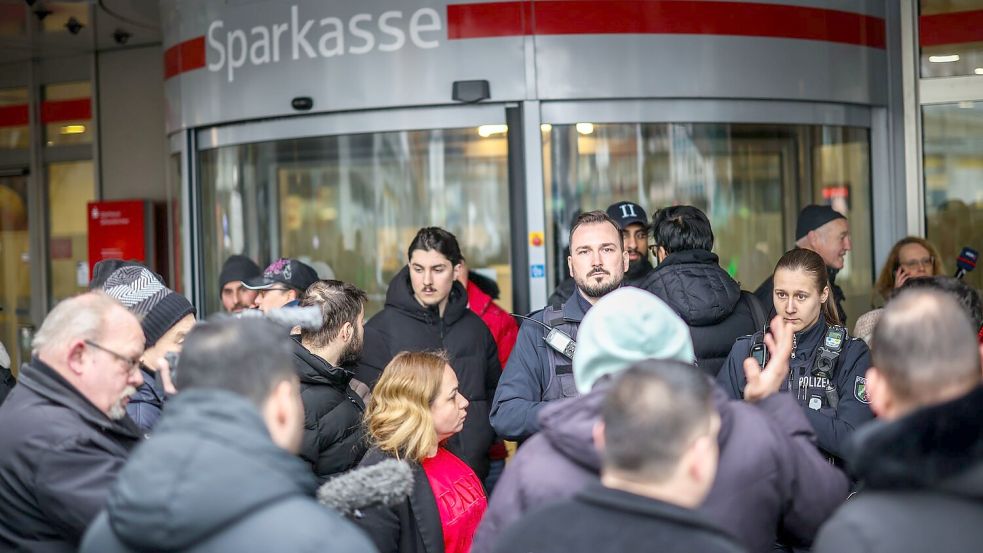 Polizeibeamte sprechen mit möglicherweise betroffenen Kunden der Sparkassenfiliale in Buer. Foto: Christoph Reichwein