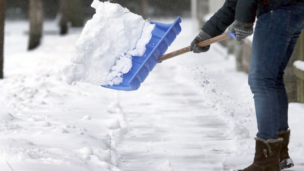 Ein Gehweg wird mit einer Schaufel vom Schnee befreit. Foto: Wolfgang Kumm/DPA