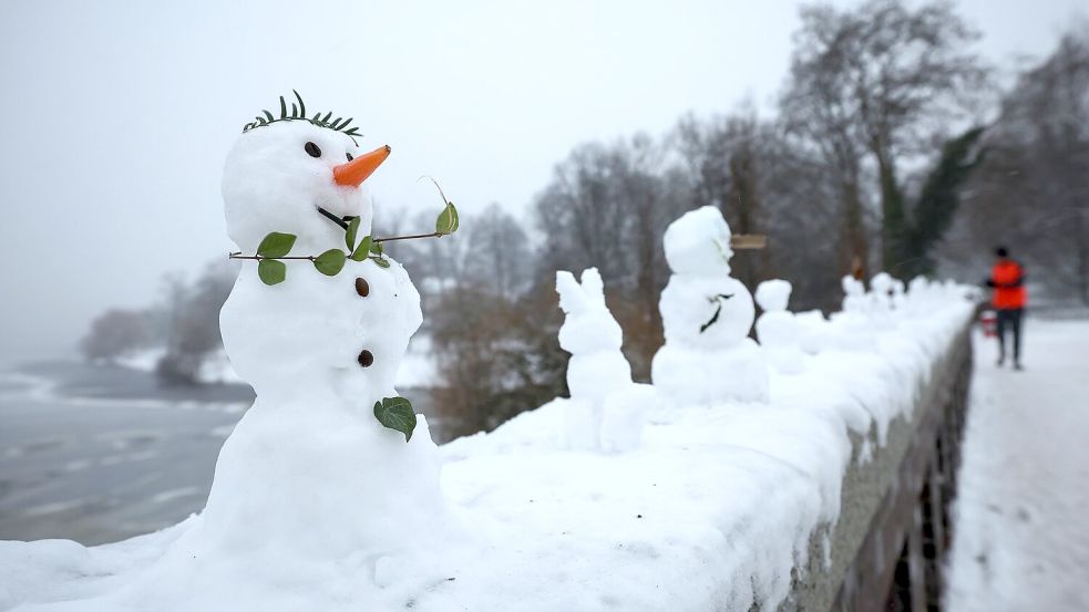 Eine ungewöhnliche Ausstellung: Zahlreiche kleine und winzige Schneefiguren stehen auf einer Mauer der Krugkoppelbrücke an der Alster im Hamburg. Foto: Christian Charisius