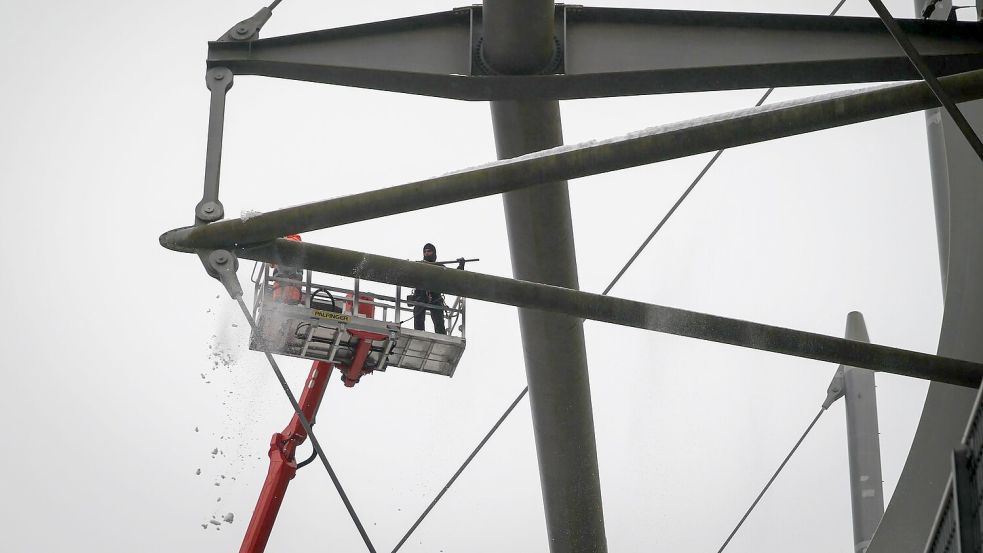 Arbeiter mit einem Hubsteiger entfernen Eis und Schnee von den Trägern des Stadiondachs in Hamburg. Foto: Christian Charisius