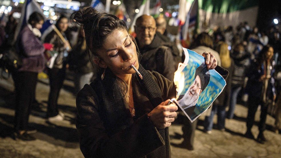Überall auf der Welt fanden Proteste in Solidarität mit den Menschen im Iran statt. In Israel zündete sich eine Frau eine Zigarette an, bevor sie mit ihrem Feuerzeug ein Bild von Ayatollah Ali Khamenei in Brand steckte. Foto: AFP/JOHN WESSELS