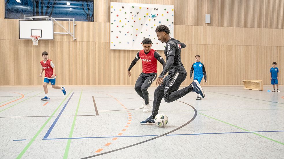 Ein schöner Besuch: Kevin Wiethaup (mit rotem Leibchen) und Tony Lesueur (am Ball) vom VfL Osnabrück schauten beim Training der D-Jugendlichen von BW Schinkel vorbei. Foto: Lauren Rote