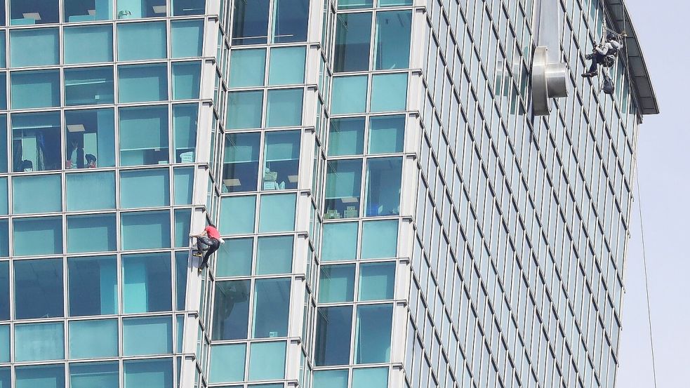 Schaulustige beobachteten Alex Honnold nicht nur vom Boden aus - auch hinter den Bürofenstern wurde der Extremsportler angefeuert. Foto: ChiangYing-ying/AP/dpa